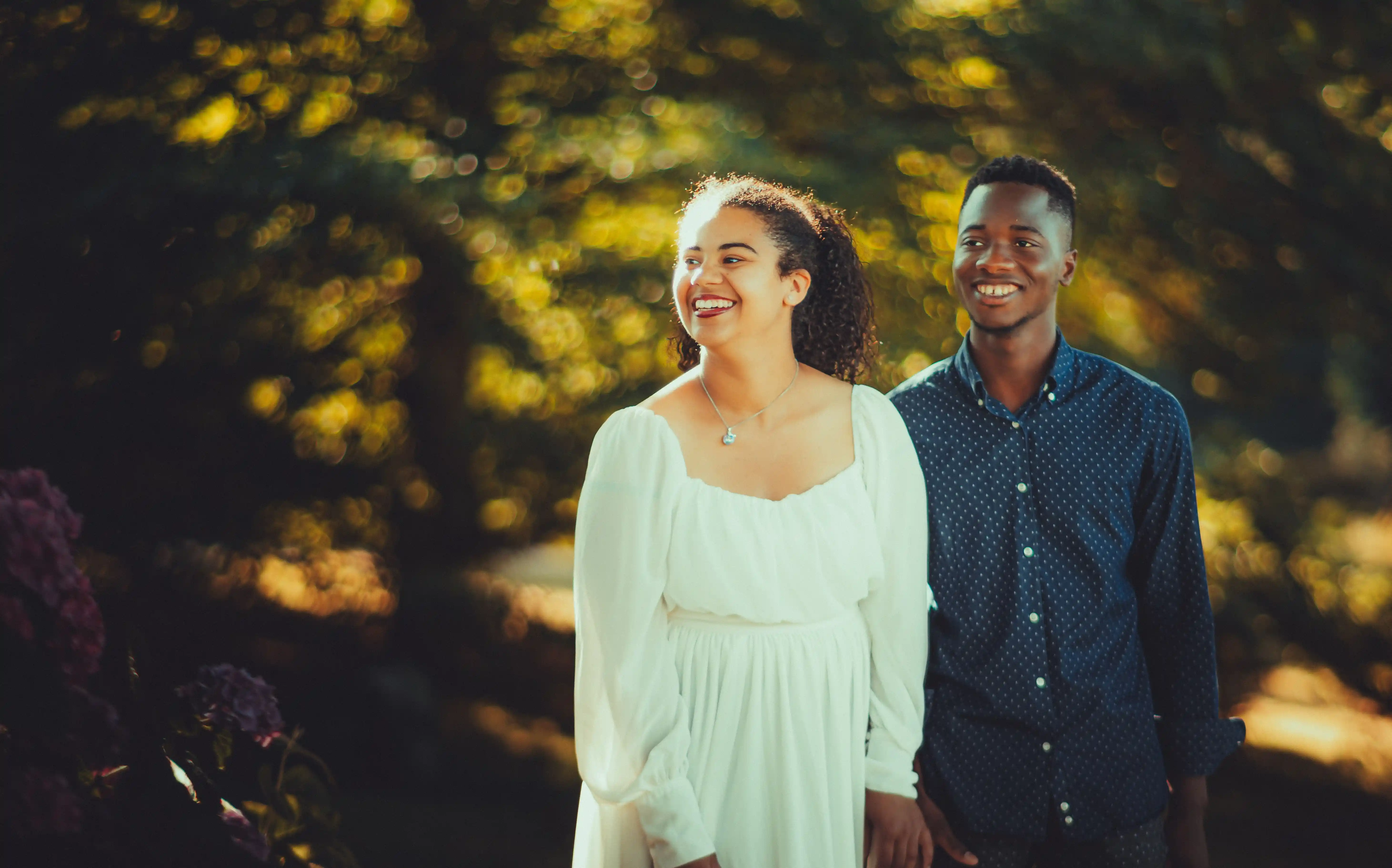 A smiling couple walking together through a sunlit garden